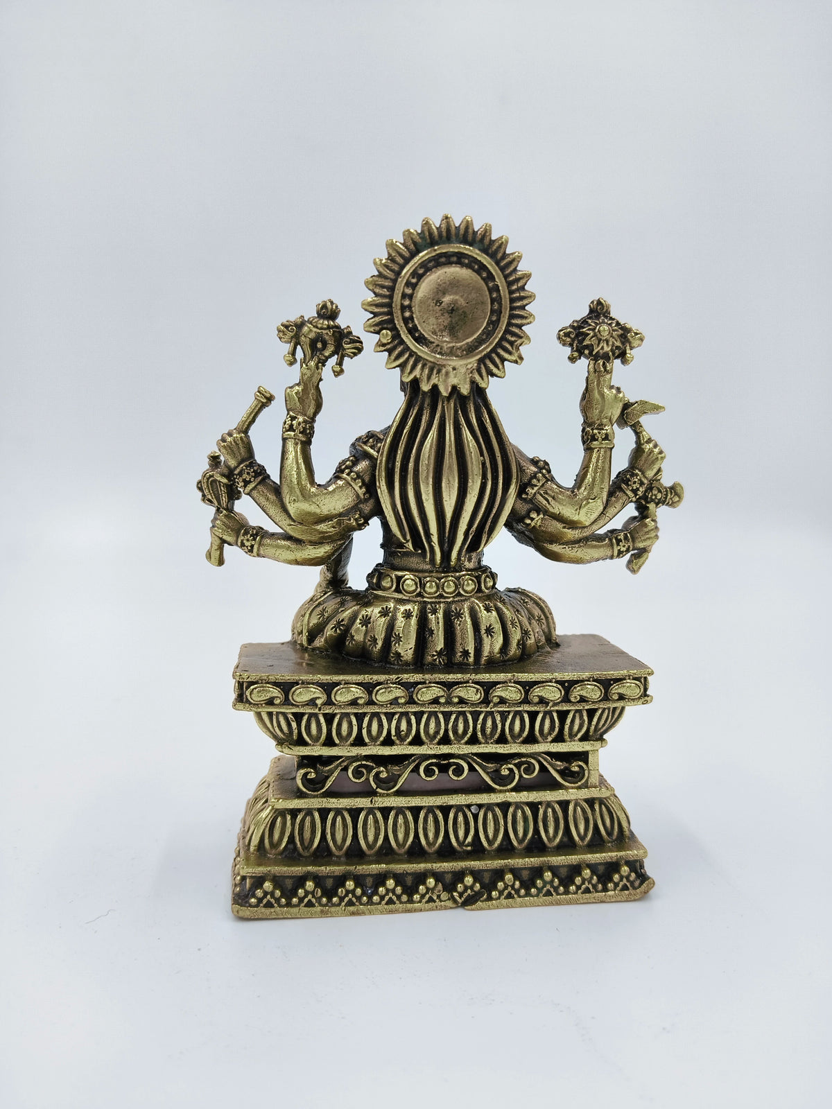 Back view of small brass Varahi statue seated on ornate pedestal