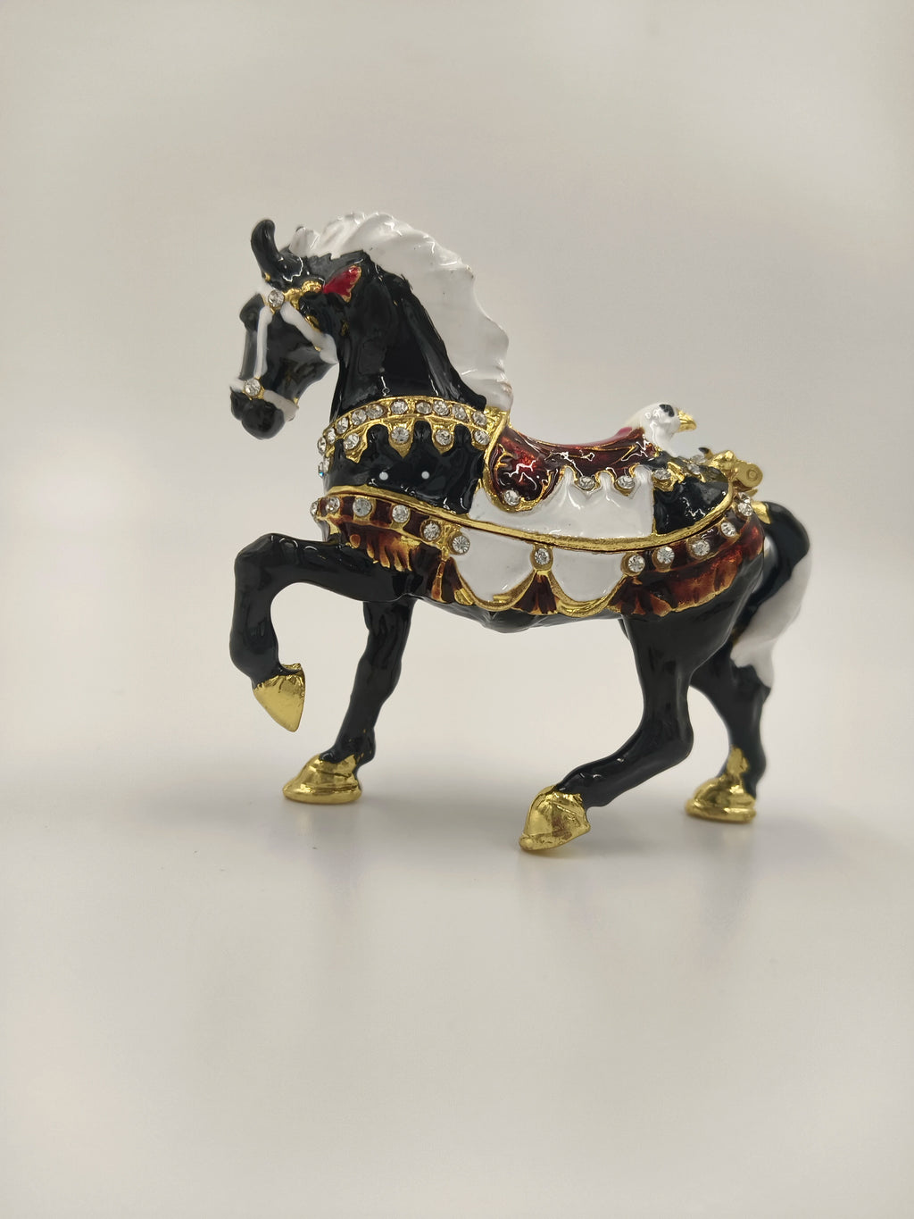 Small black horse figurine with white mane, gold hooves, and decorative saddle