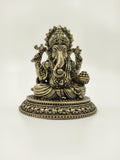 Small brass Ganesh sculpture seated with decorative base and detailed carvings