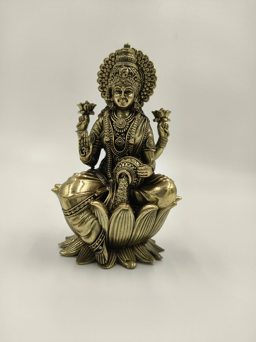 Brass statue of Lakshmi goddess seated on a lotus flower holding lotuses