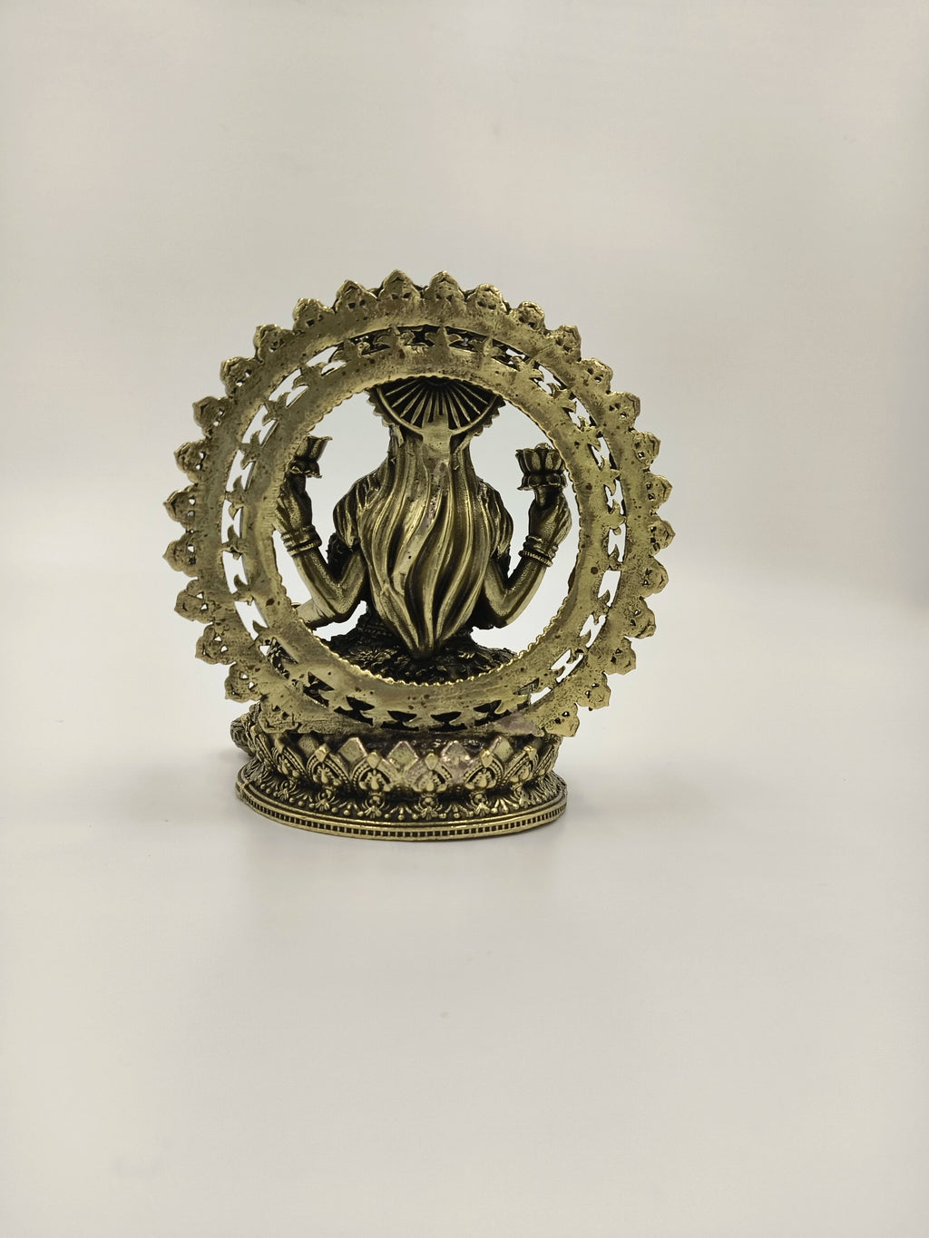 Back view of small brass Lakshmi sculpture with decorative arch