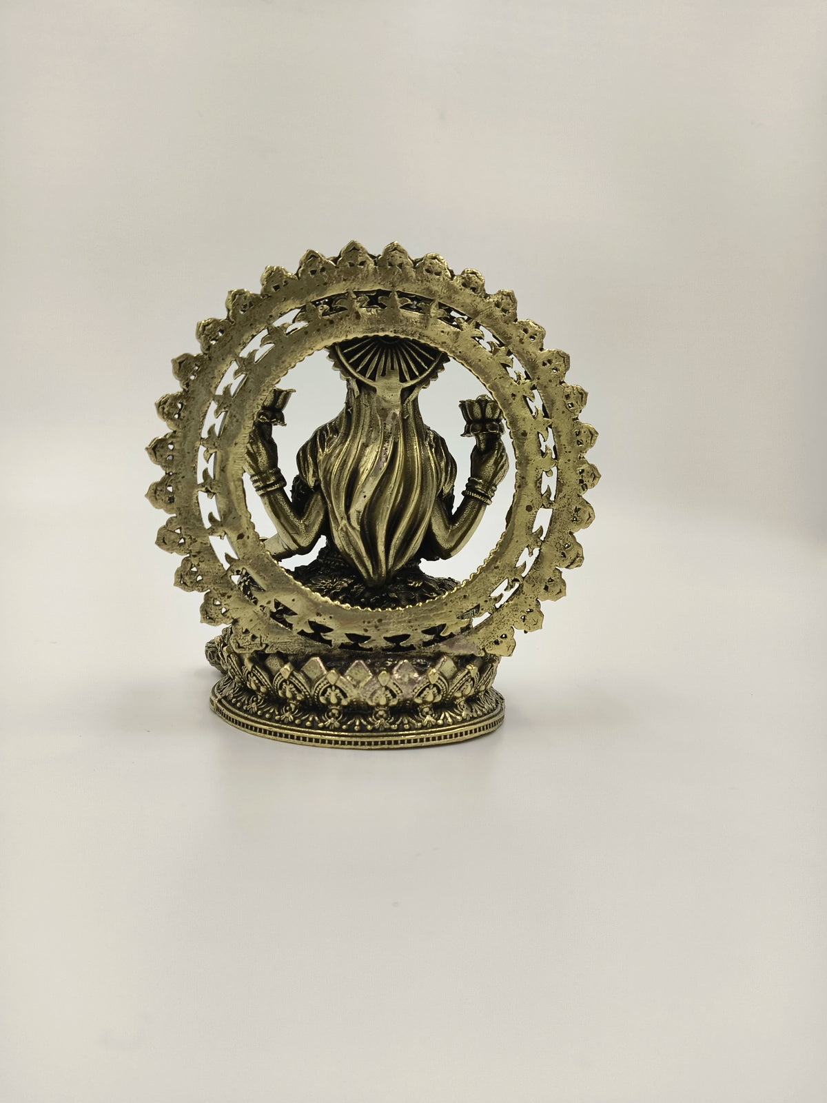 Back view of small brass Lakshmi sculpture with decorative arch
