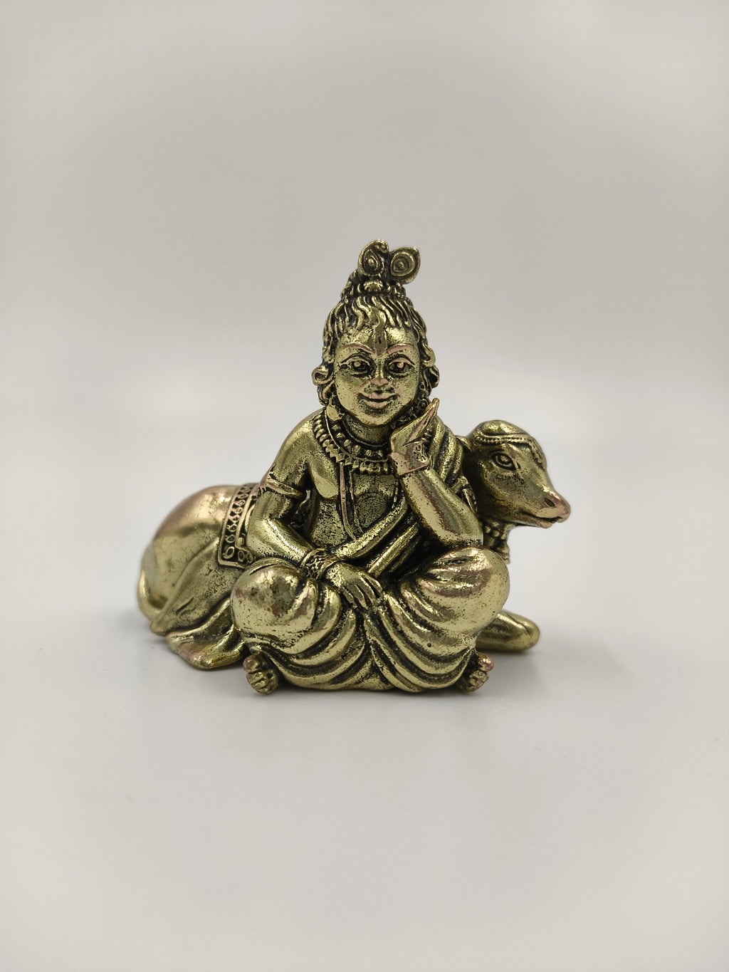 Mini brass sculpture of Krishna sitting beside a cow