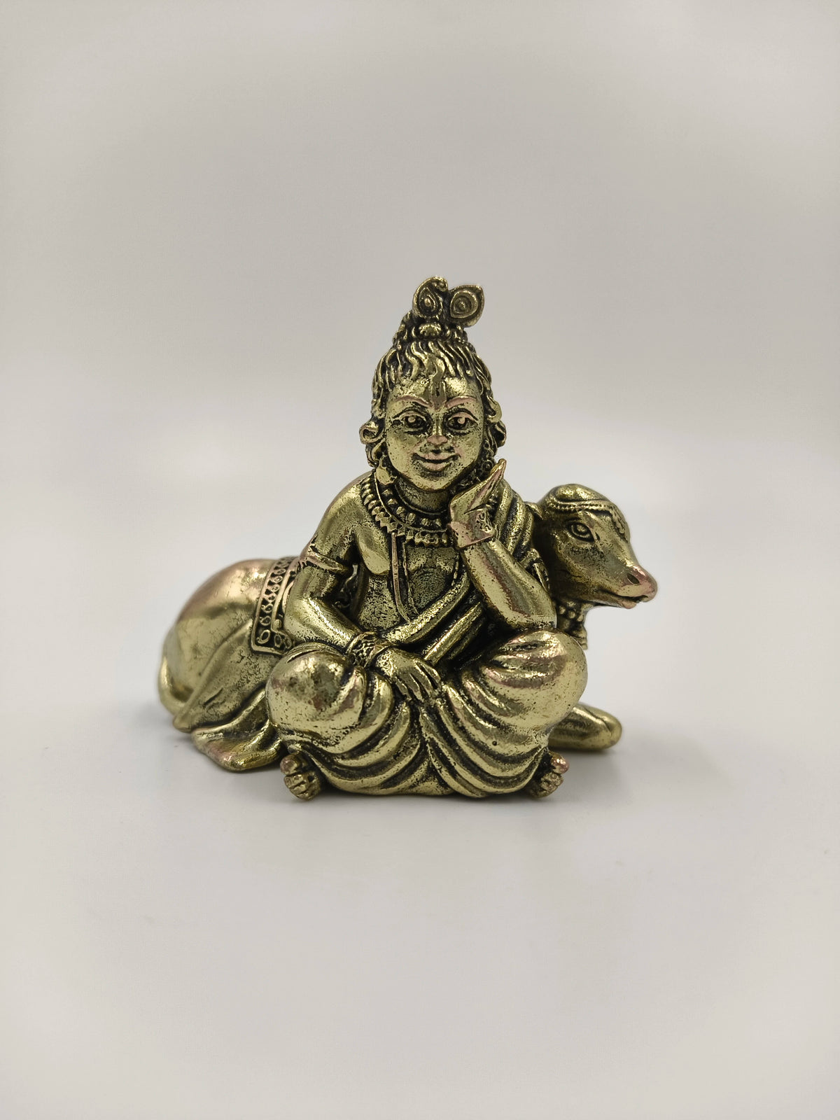 Mini brass sculpture of Krishna sitting beside a cow