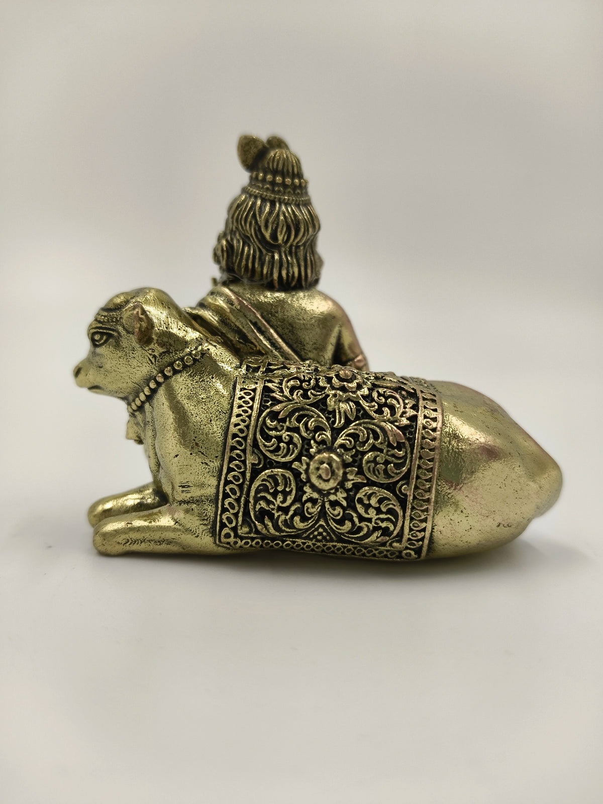 Mini brass sculpture of Krishna seated with a decorated cow from side view