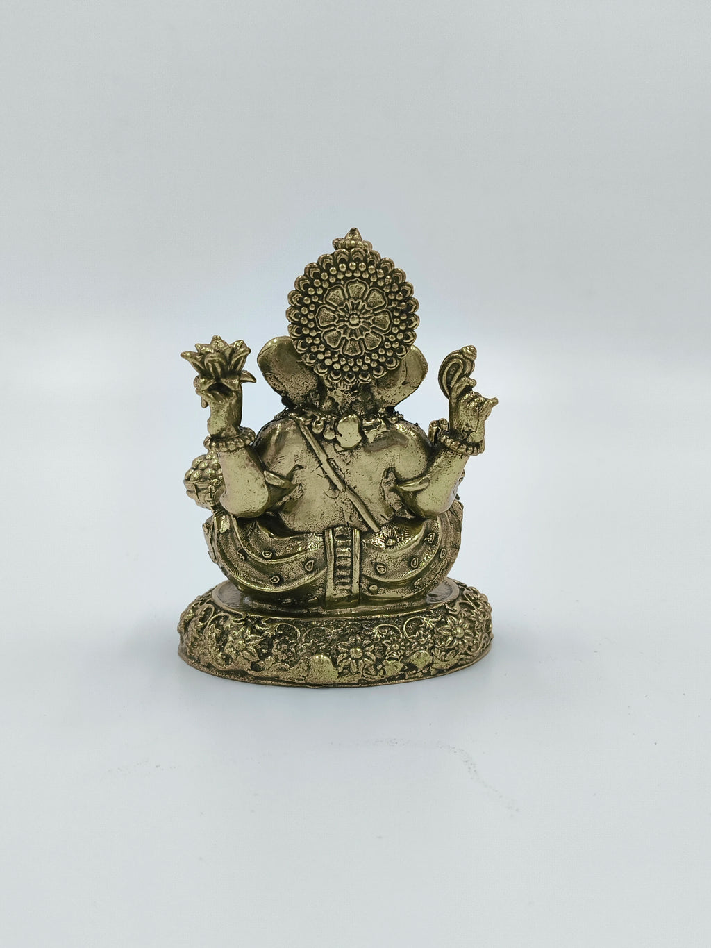 Back view of small brass Ganesh statue seated on a detailed base