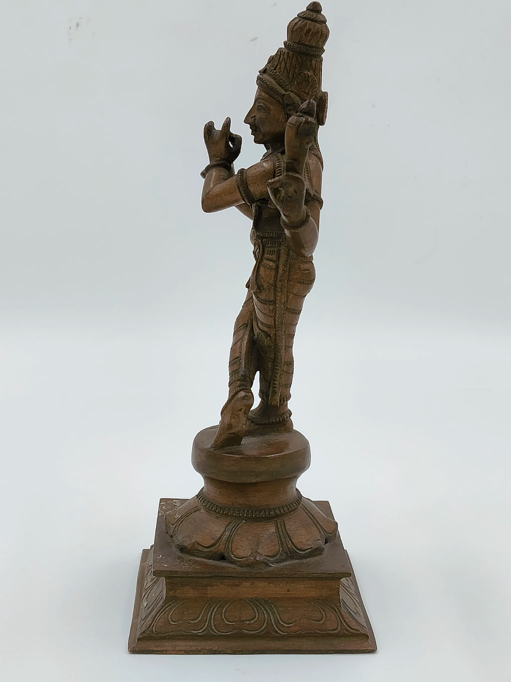 Side view of bronze Krishna statue with detailed carvings on square base
