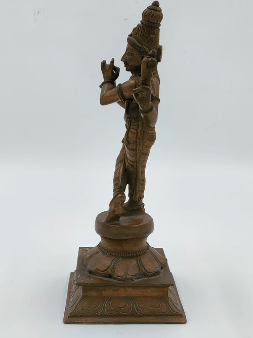 Side view of bronze Krishna statue with detailed carvings on square base
