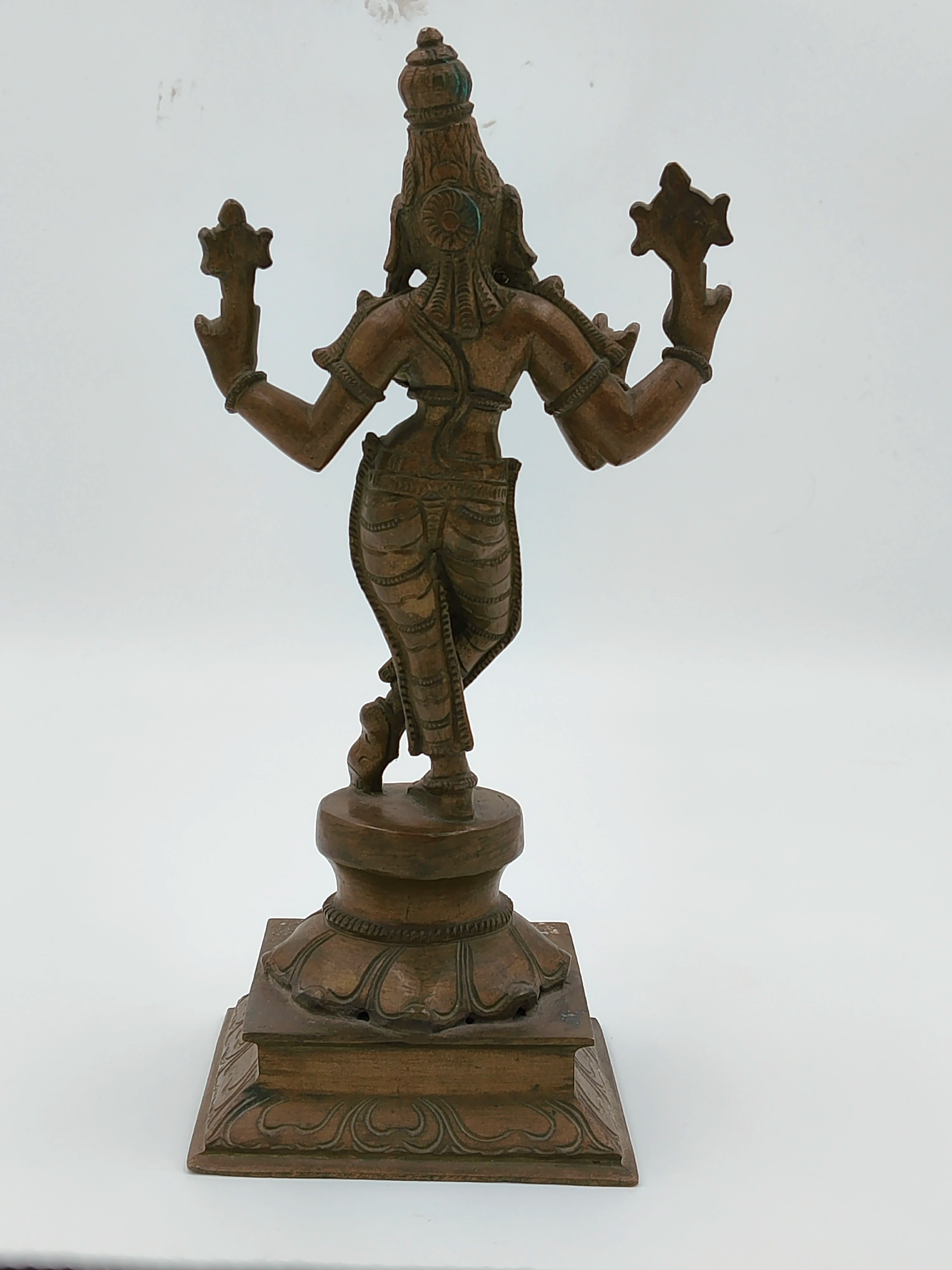 Back view of large bronze Krishna sculpture standing on decorative square base