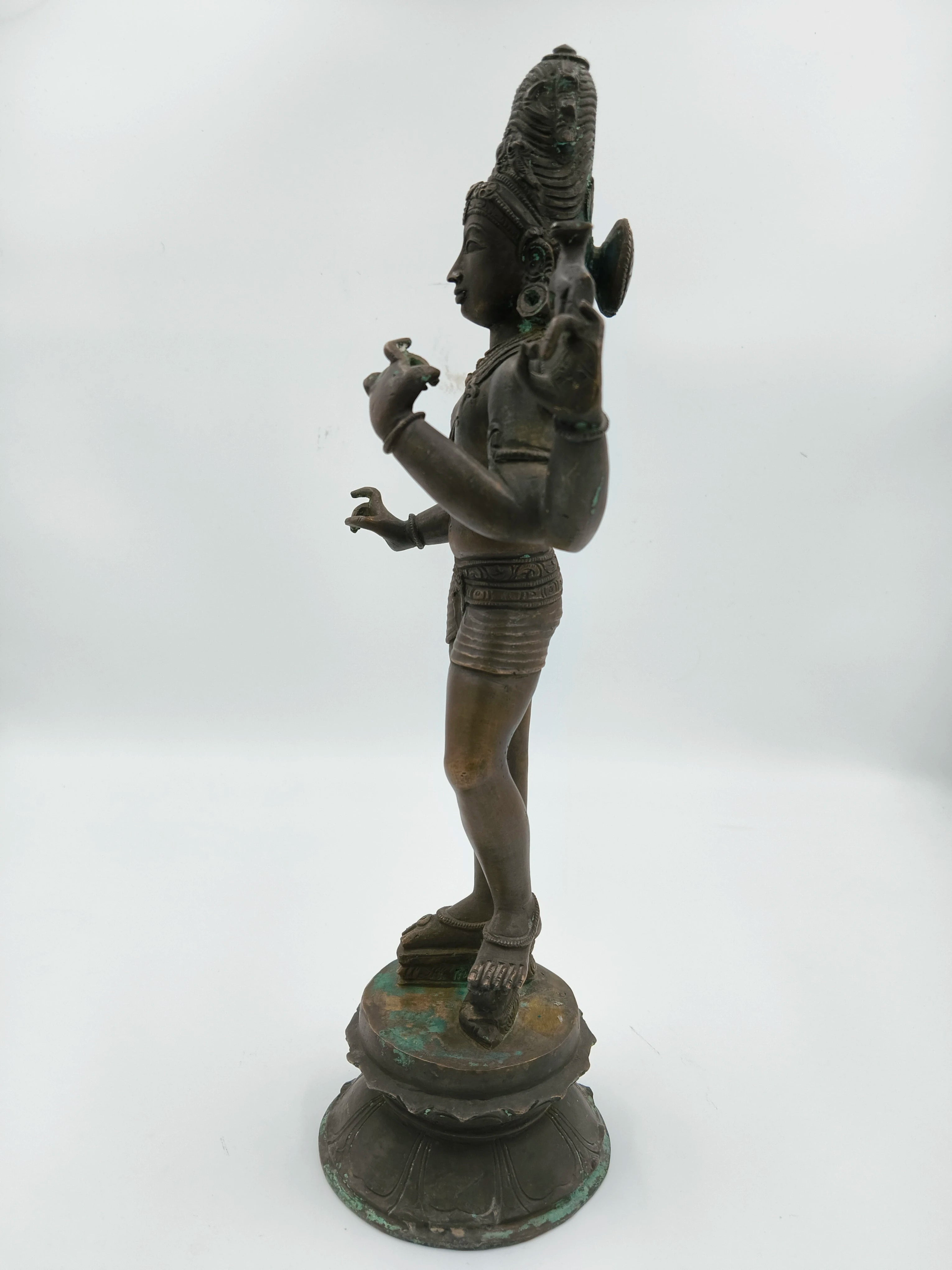 Side view of a large bronze standing Shiva sculpture on a lotus base