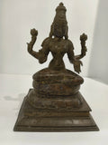 Large bronze Lakshmi statue seated with four arms holding lotus flowers on decorated base