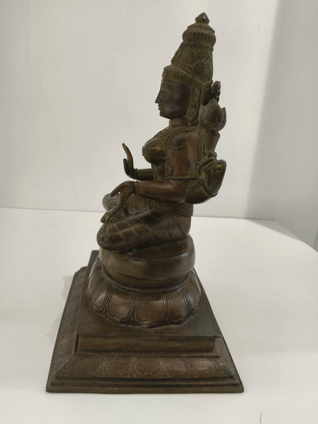 Large bronze Lakshmi statue seated on a decorated base, side view