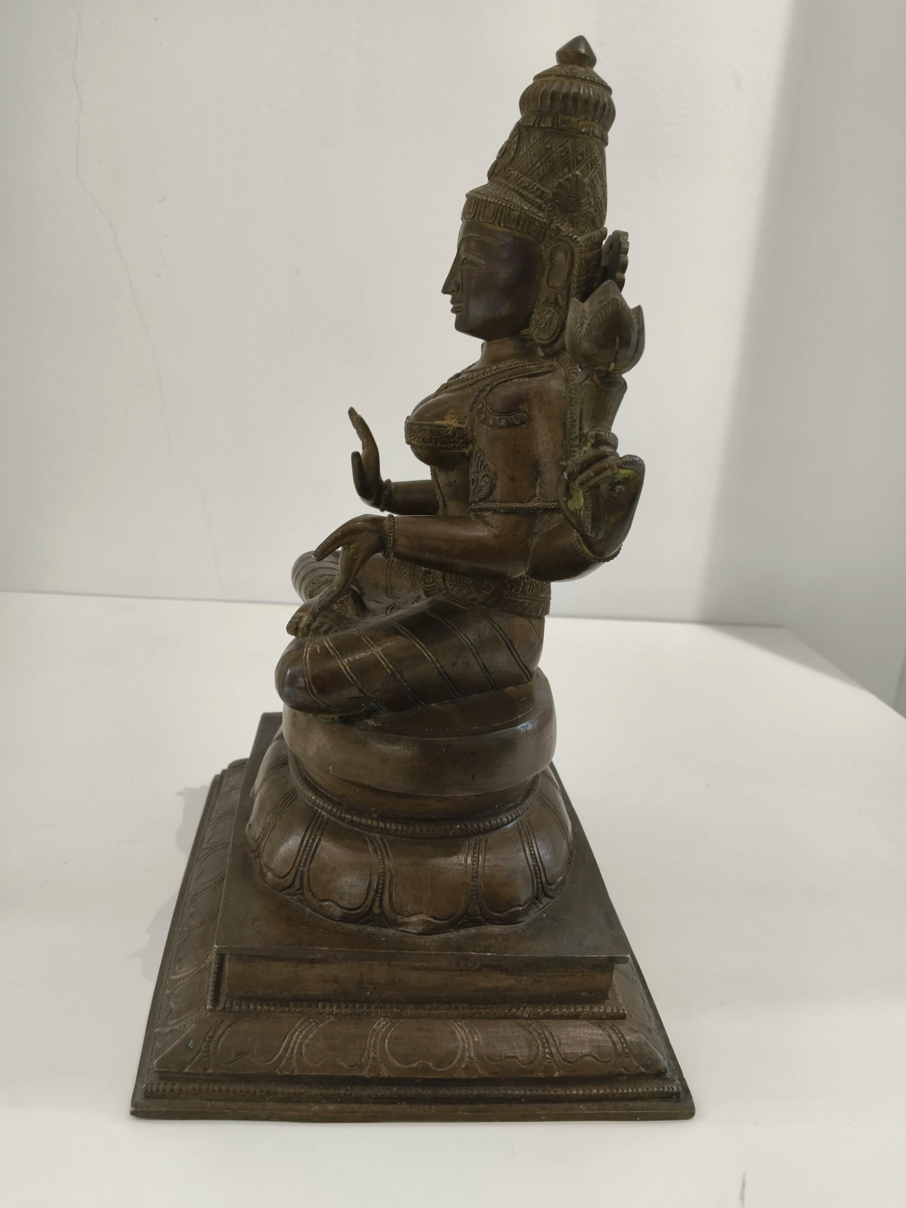 Large bronze Lakshmi statue seated on a decorated base, side view