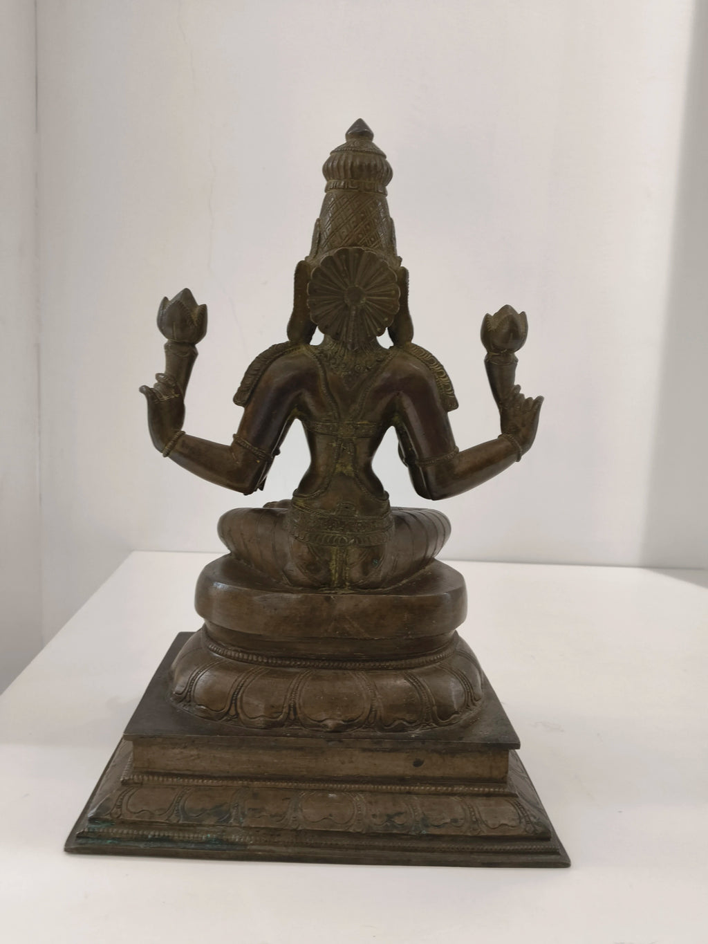 Back view of large bronze statue of deity Lakshmi seated on lotus pedestal