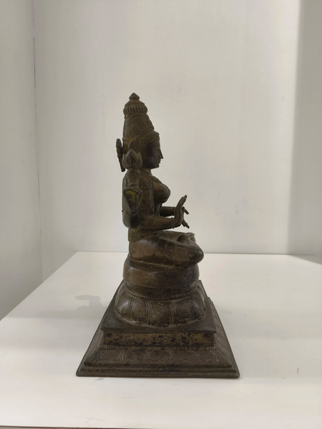 Large bronze statue of deity Lakshmi sitting on lotus pedestal side view