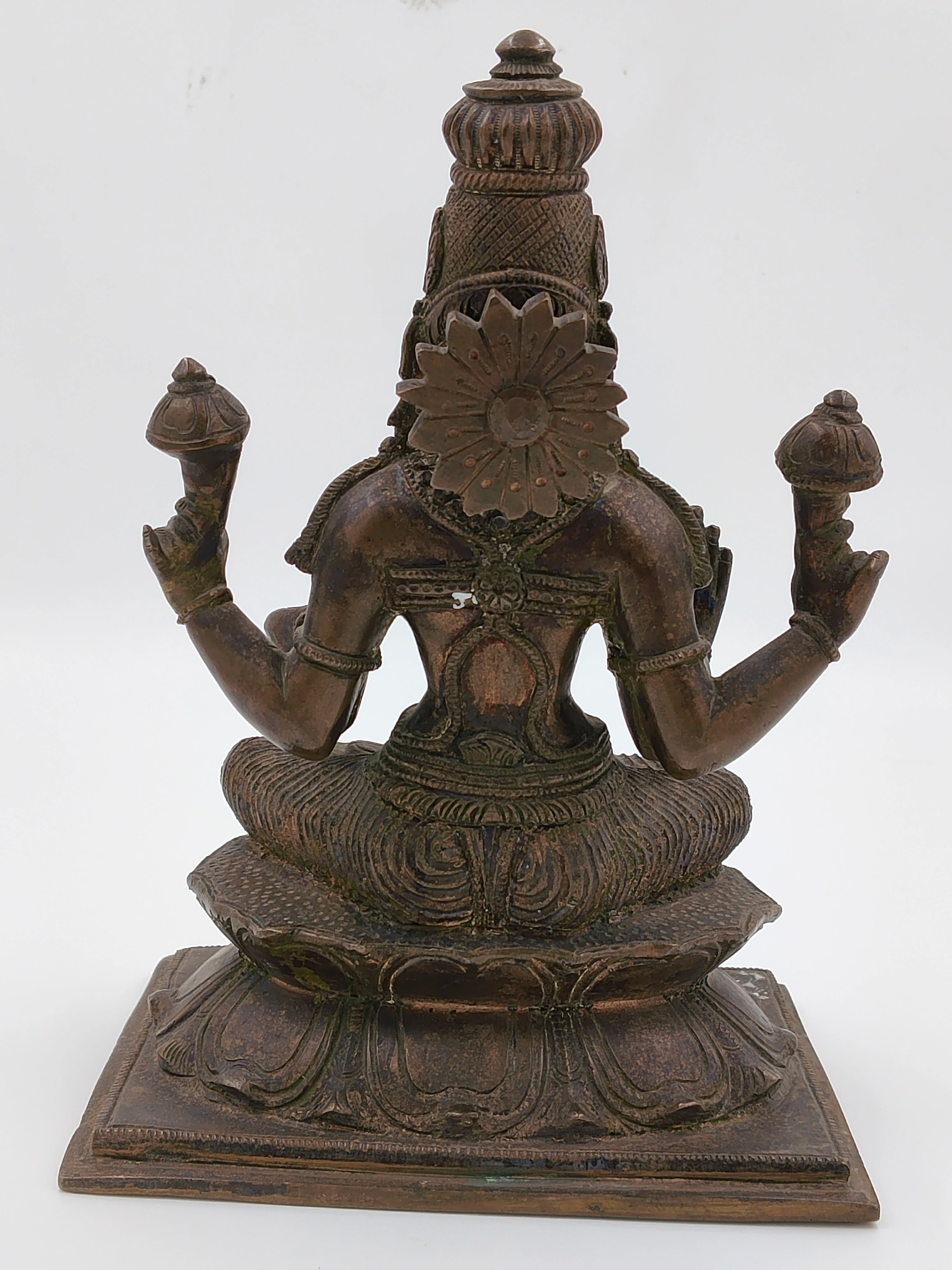 Back view of bronze Lakshmi statue seated on lotus pedestal