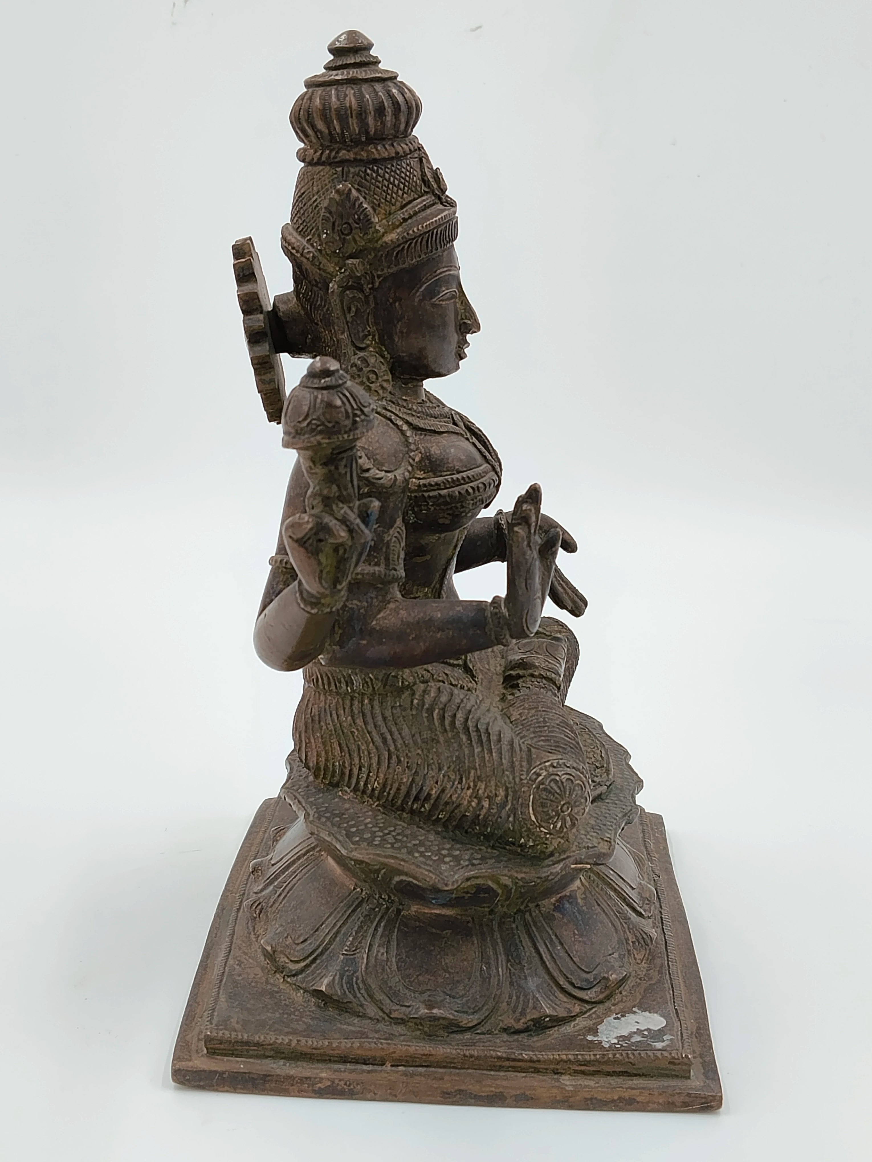 Side view of bronze Lakshmi statue seated on lotus base