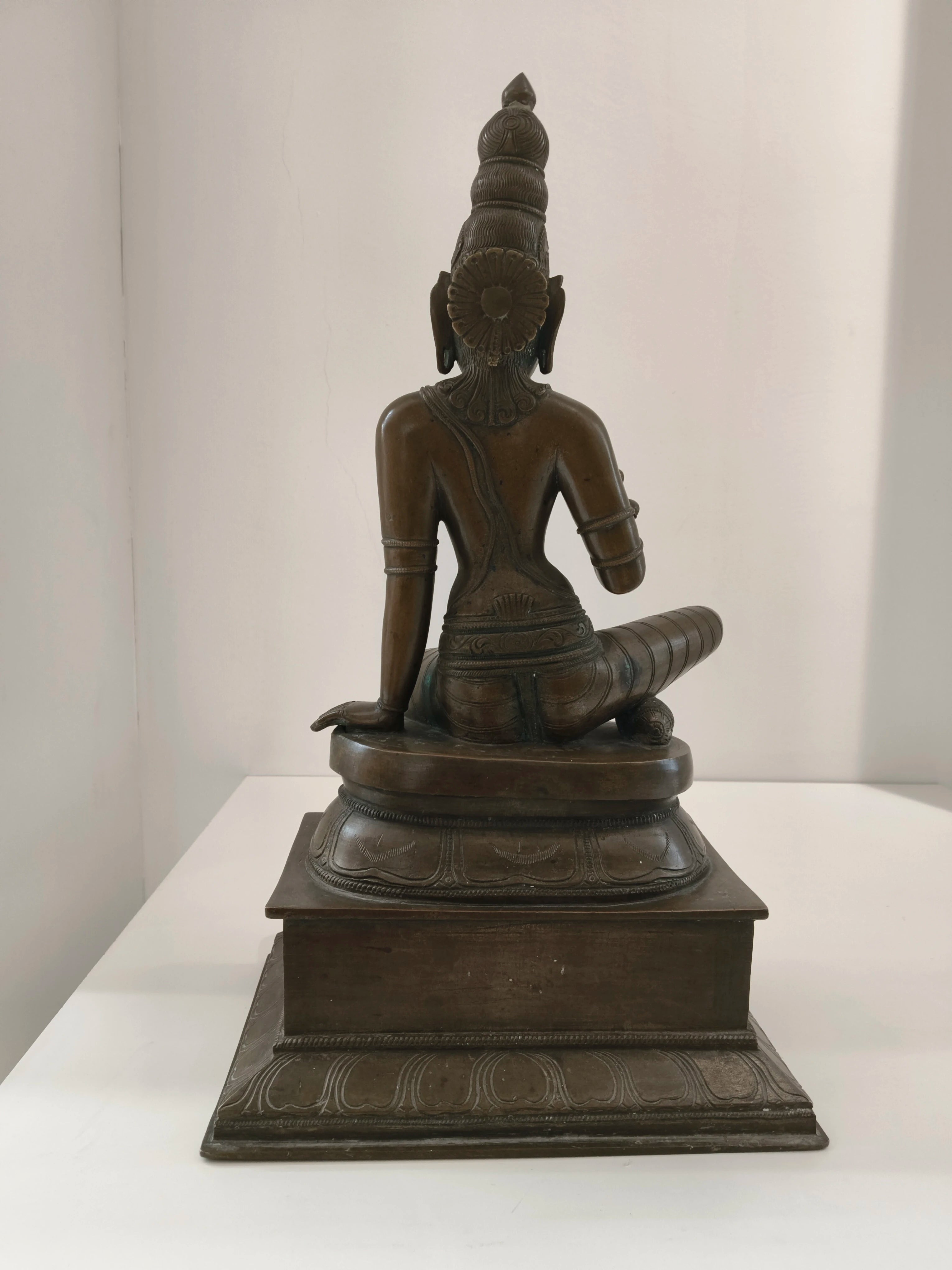 Large bronze statue of Goddess Parvathi sitting on a decorative base, back view