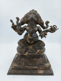 Bronze statue of four-faced Ganesh sitting on a decorated pedestal