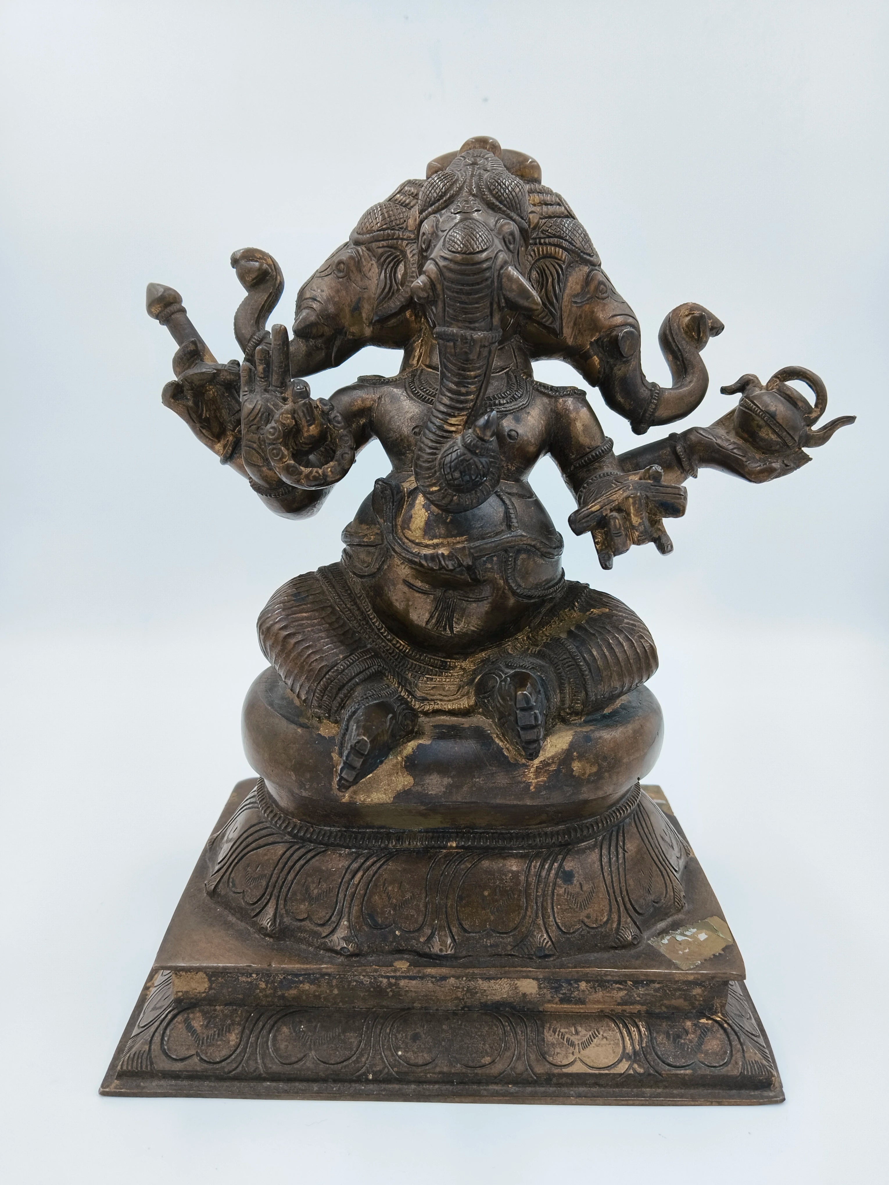 Bronze statue of four-faced Ganesh sitting on a decorated pedestal