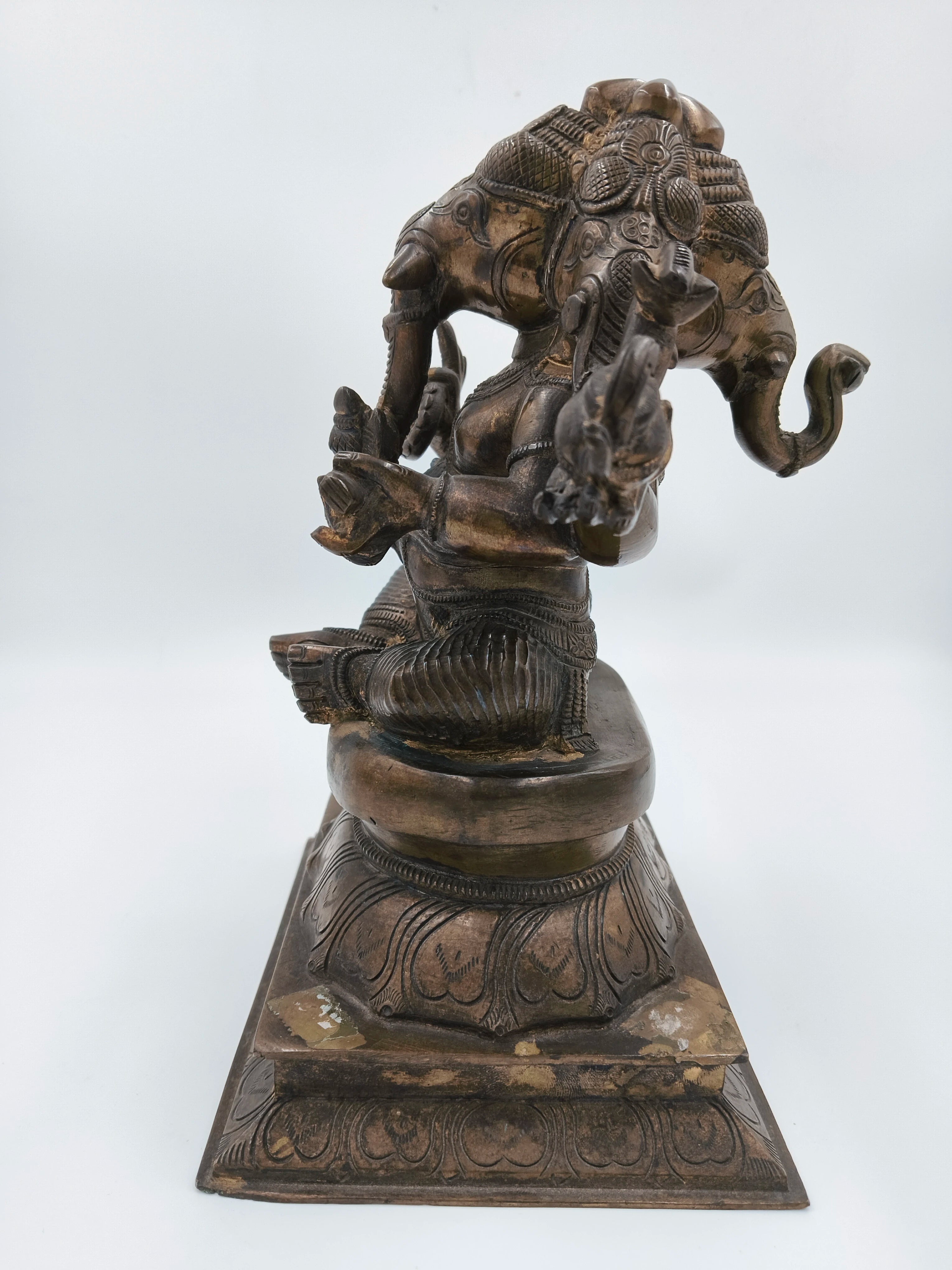 Bronze four-faced Ganesh statue seated on decorated pedestal, side view