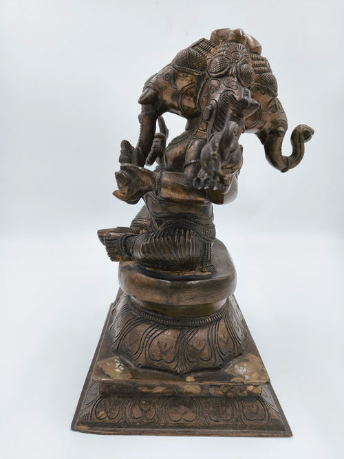 Bronze four-faced Ganesh statue seated on decorated pedestal, side view
