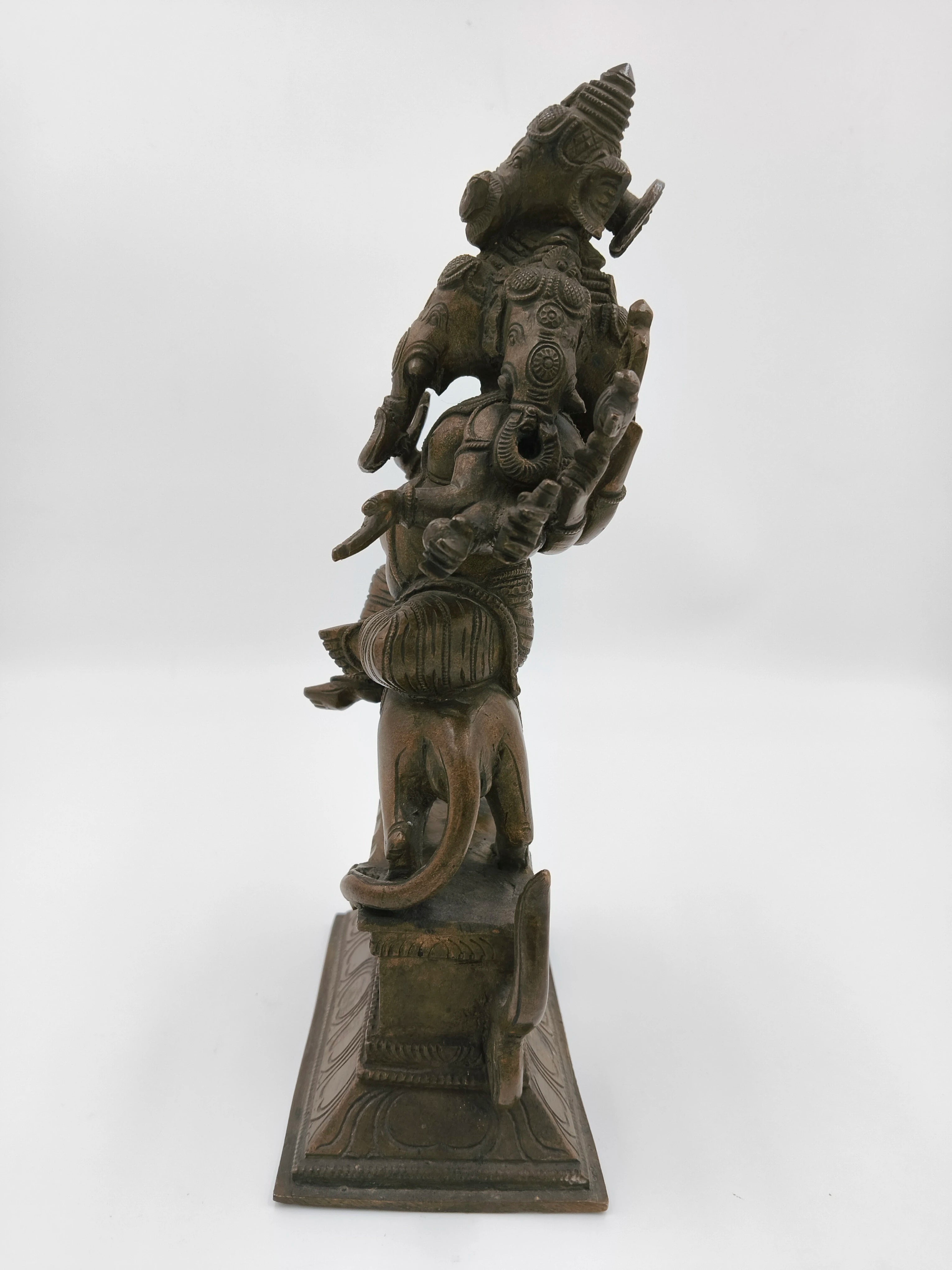 Side view of large bronze Ganesh sculpture with five faces on decorative base