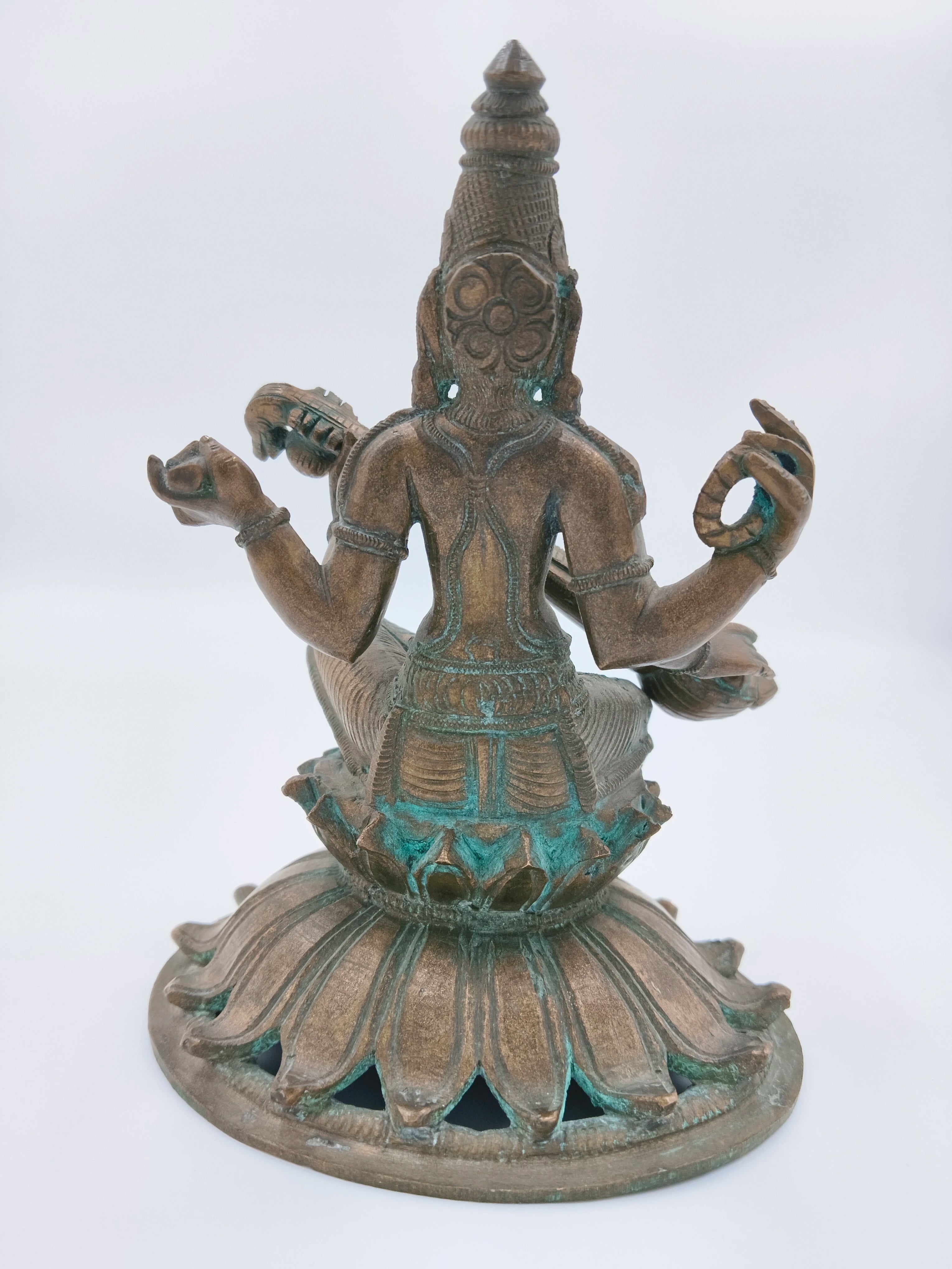 Back view of bronze Saraswathi sculpture seated on lotus base