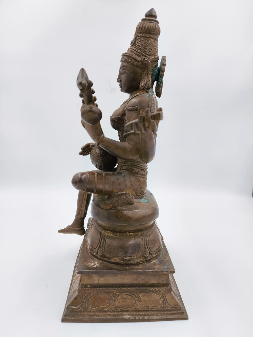 Side view of large bronze Saraswathi statue seated on a pedestal