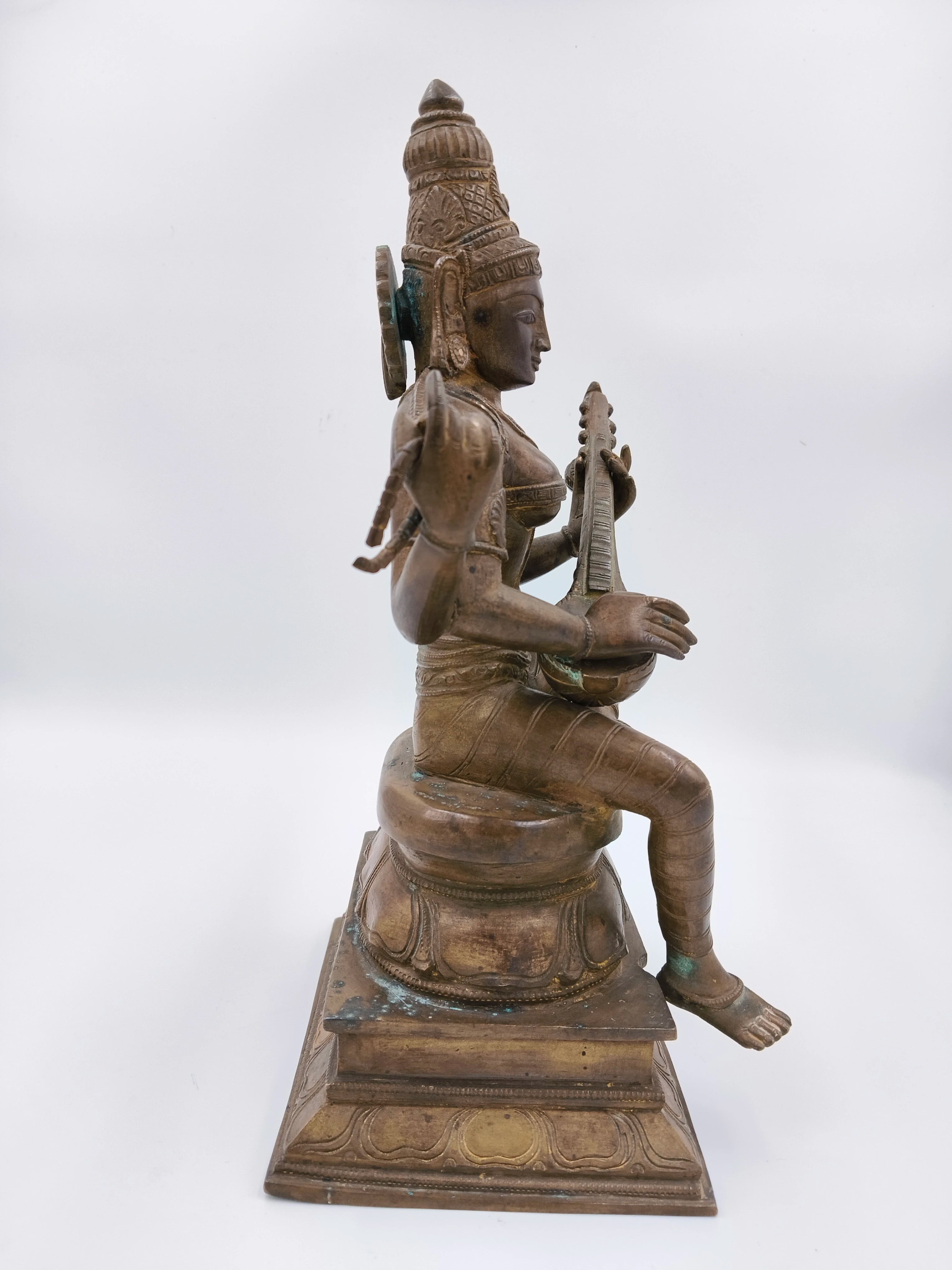 Side view of large bronze Saraswathi statue seated playing veena