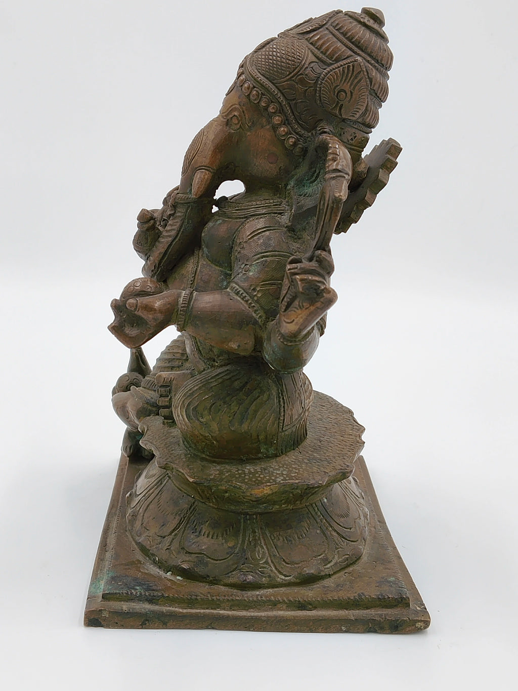 Side view of a large bronze Ganesh statue seated on a lotus pedestal