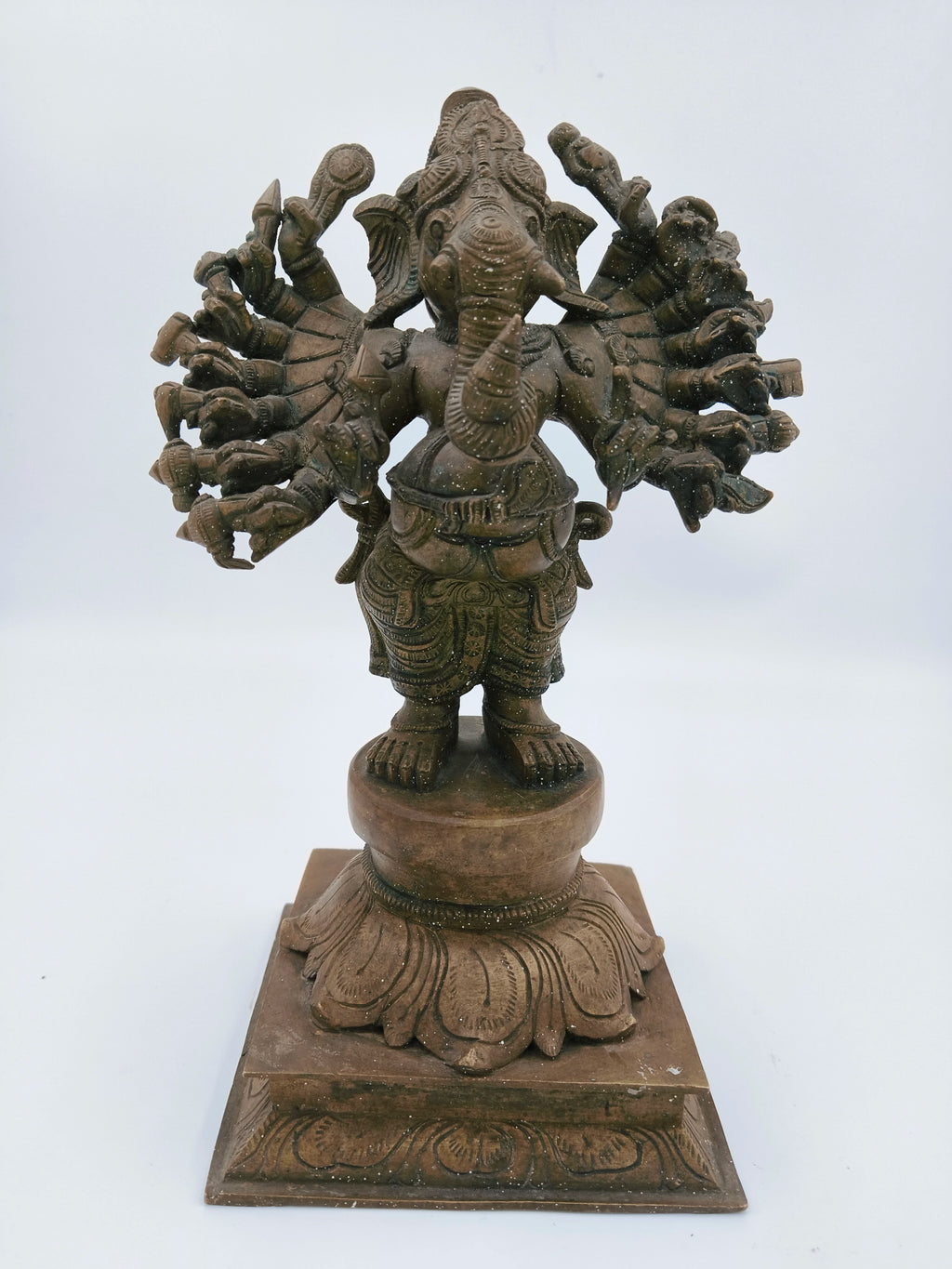 Front view bronze Ganesh statue with multiple arms on decorative pedestal