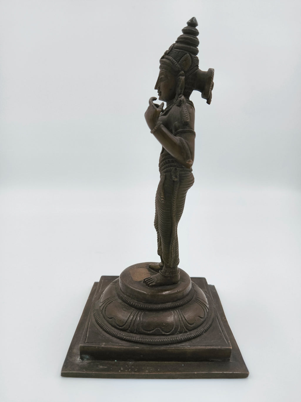 Side view of bronze Parvathi statue standing on decorated pedestal