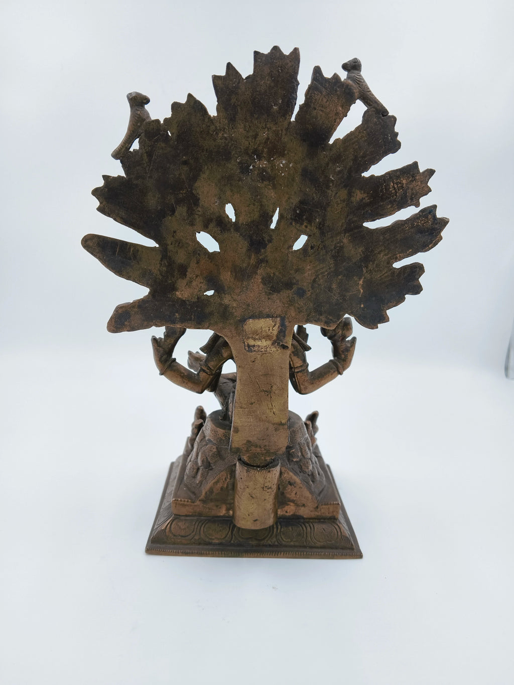 Back view of a bronze Dakshanamurthi sculpture with intricate details and a decorative base