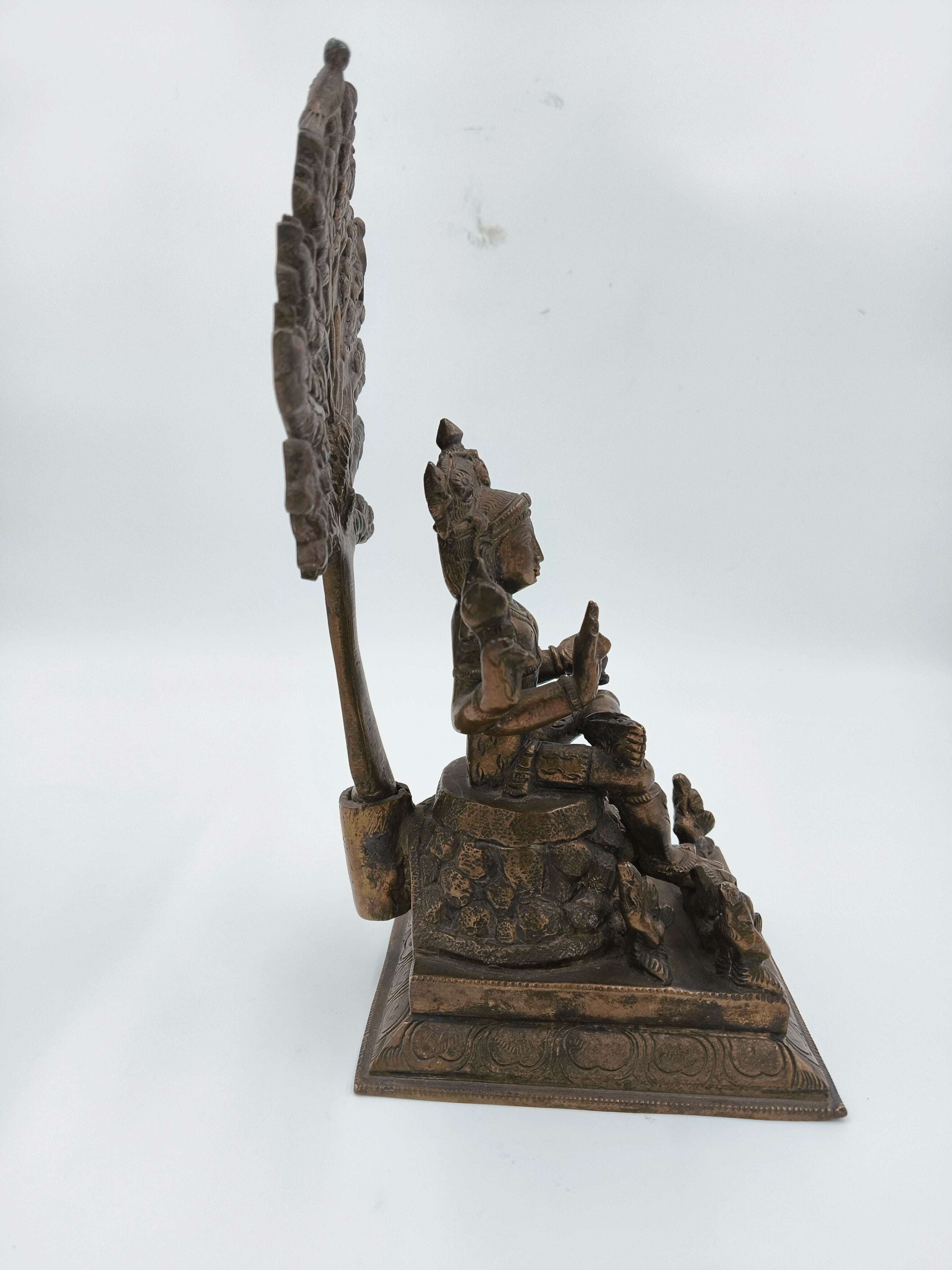 Side view of a large bronze Dakshanamurthi sculpture seated on a square base
