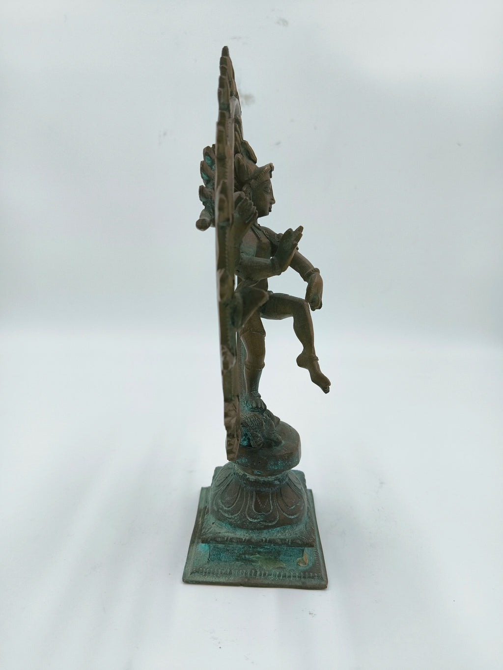 Side view of bronze Nataraja sculpture with detailed base and raised leg
