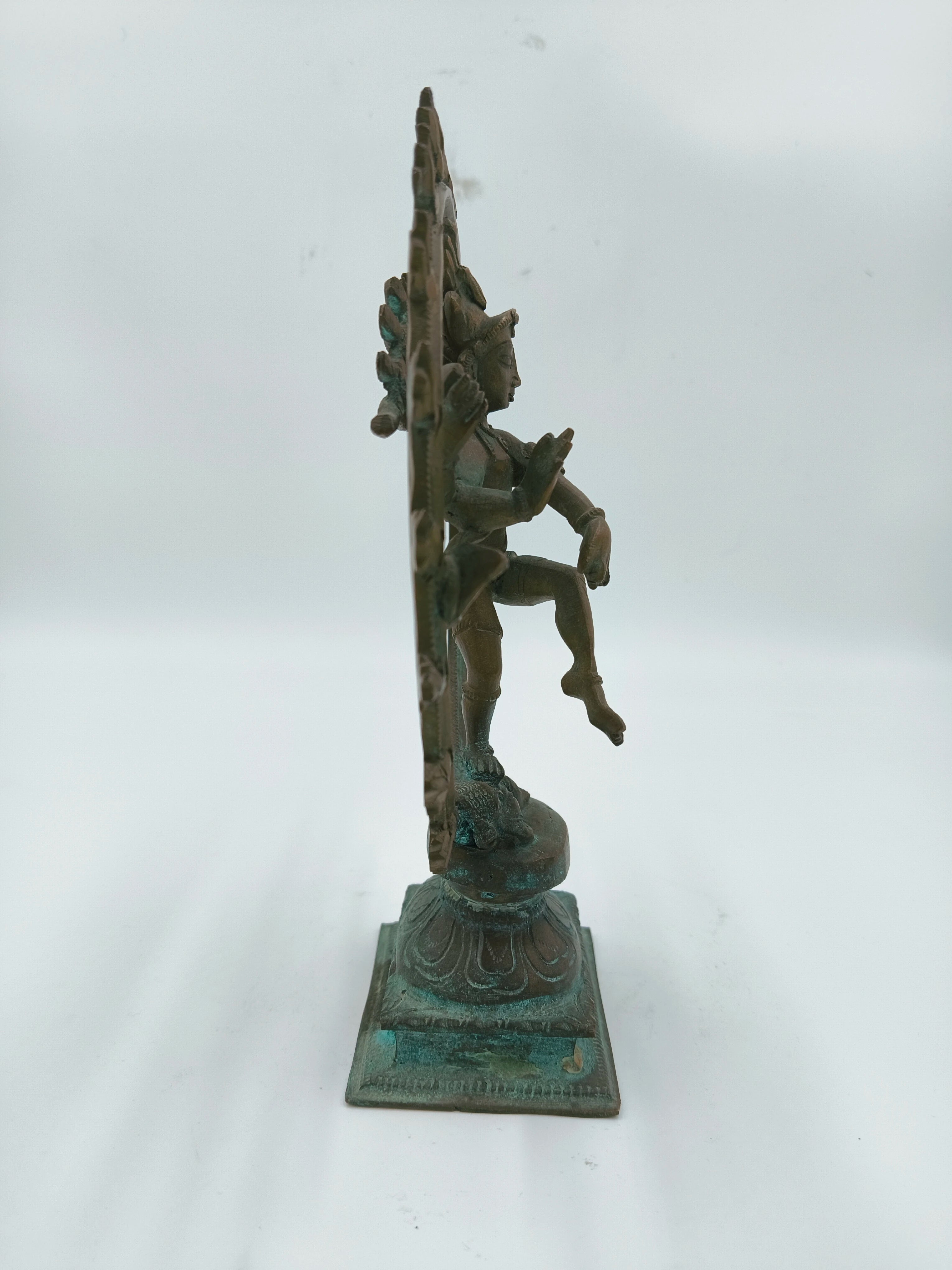 Side view of bronze Nataraja sculpture with detailed base and raised leg