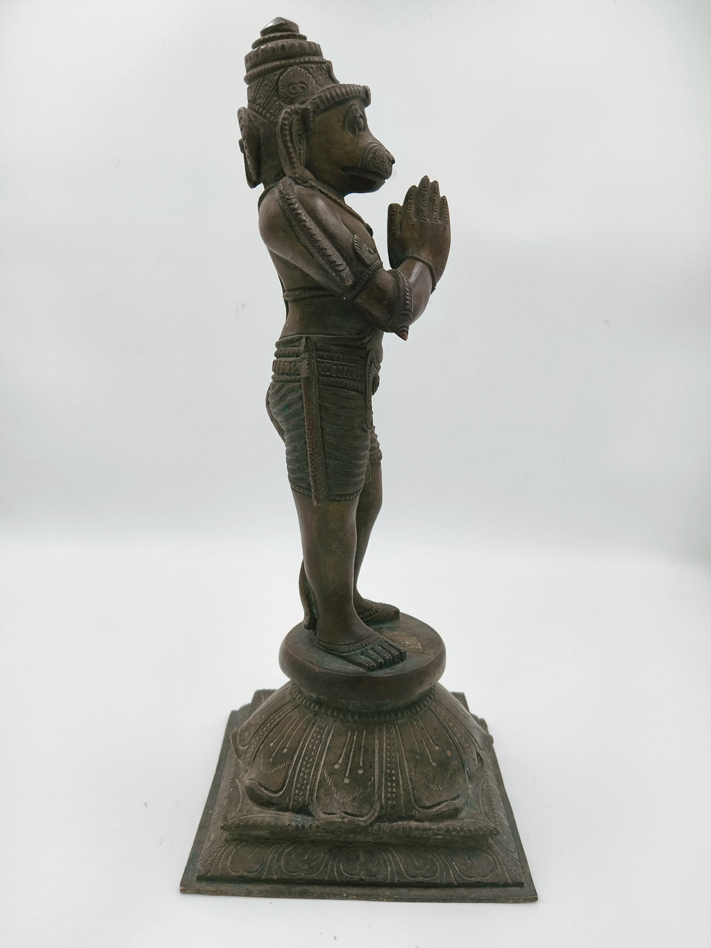 Side view of bronze Hanuman statue standing with hands in namaskaram pose