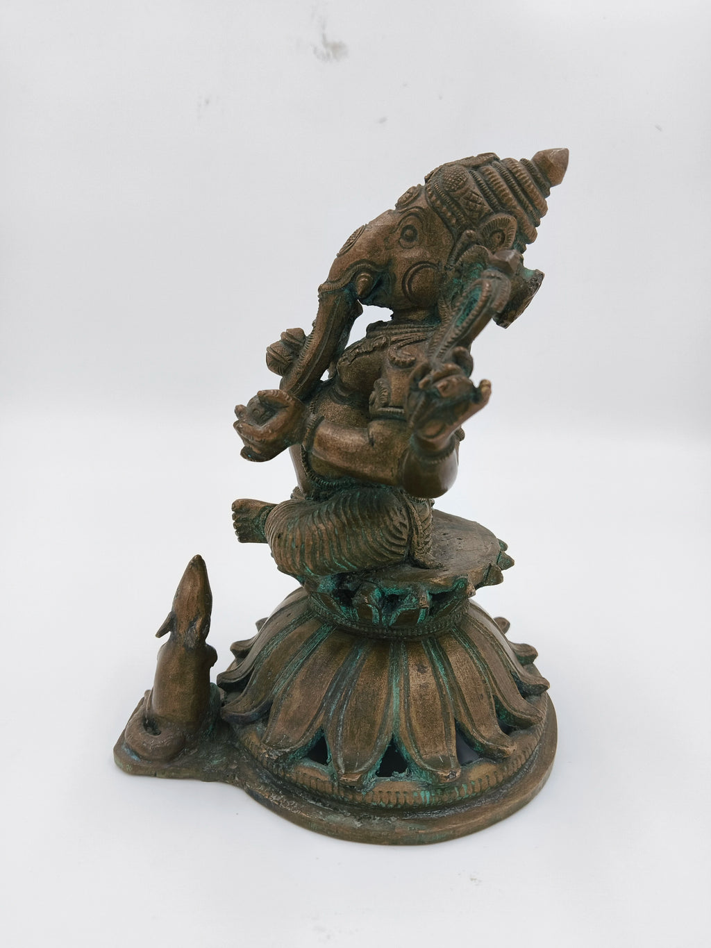Side view of bronze Ganesh sculpture sitting on lotus base with mice