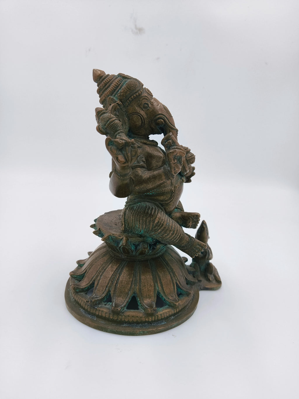 Side view of bronze Ganesh statue seated on lotus base with mice detail