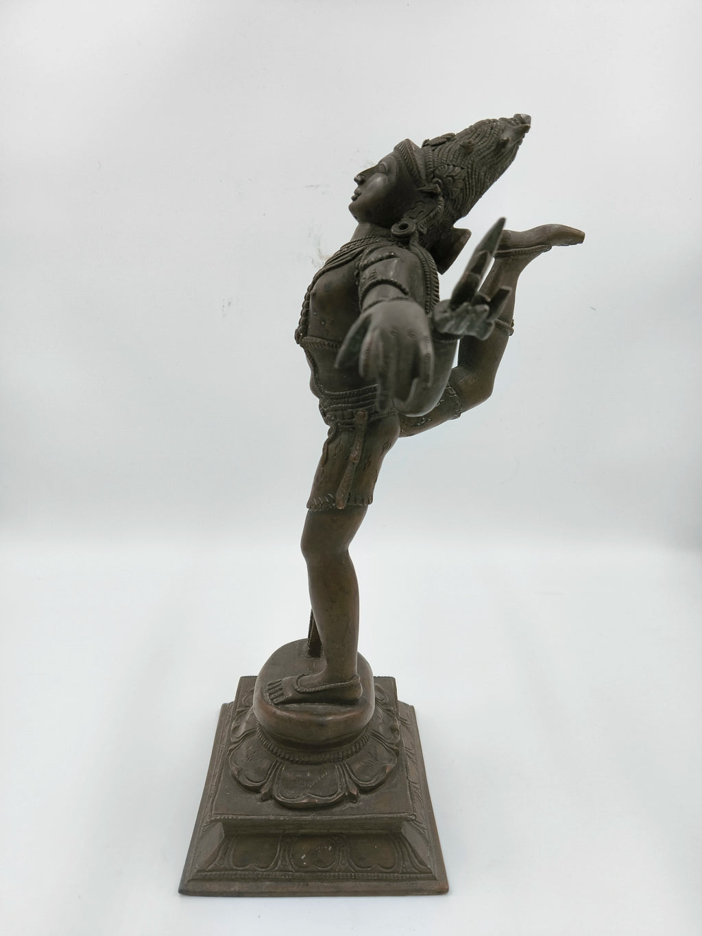 Side view of bronze Nataraja statue standing on decorative pedestal