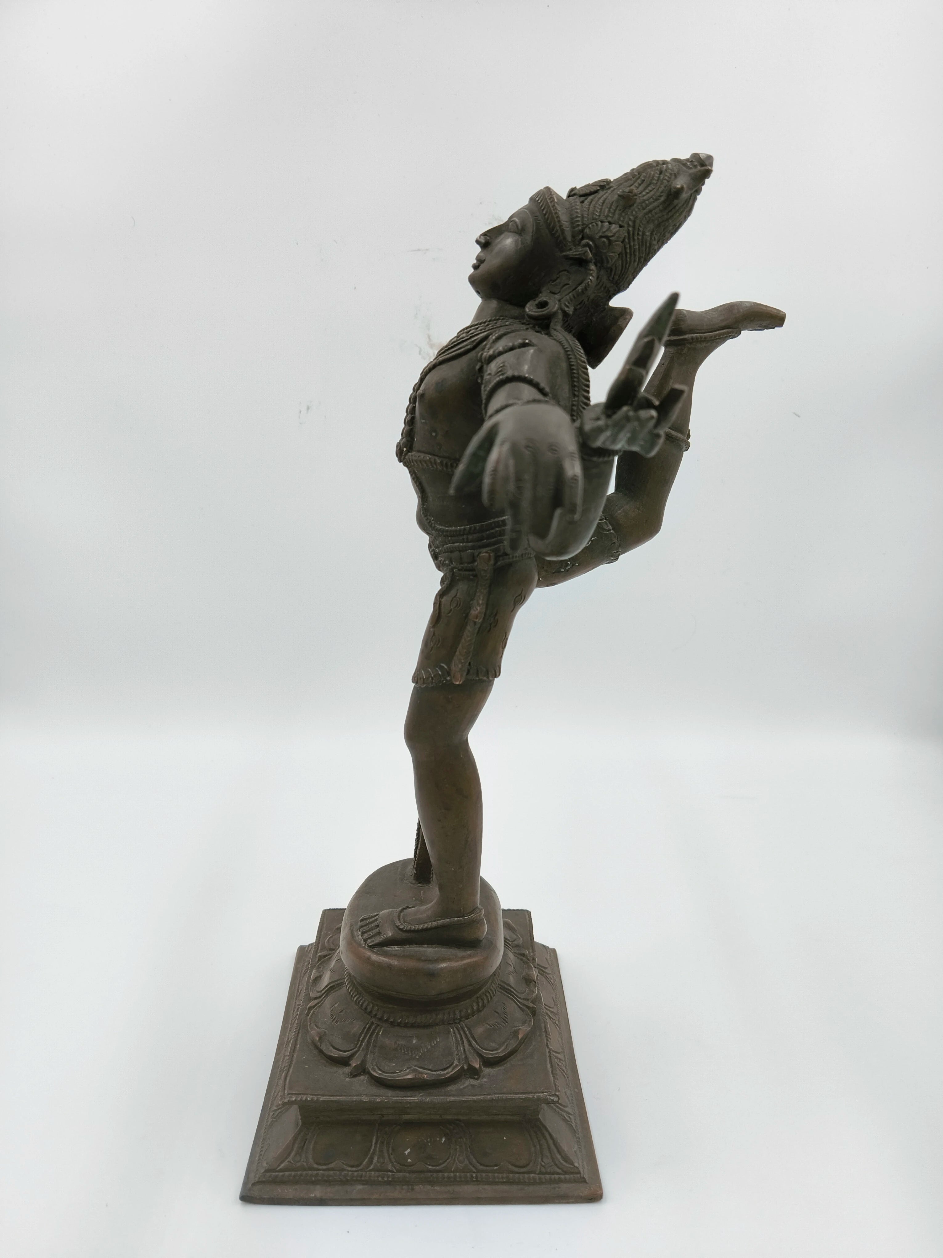 Side view of bronze Nataraja statue standing on decorative pedestal