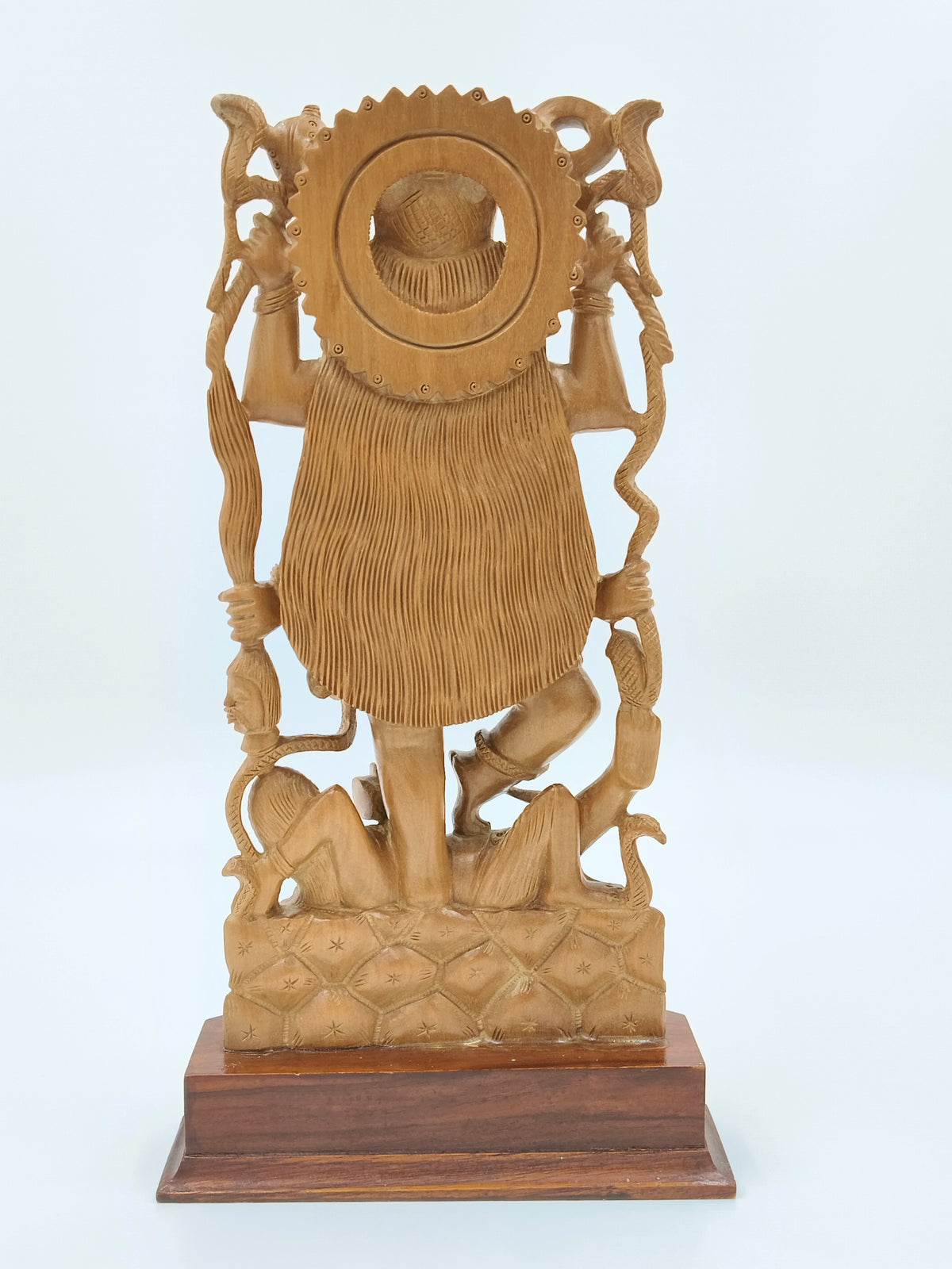 Back view of large sandalwood Kali idol standing on a wooden base