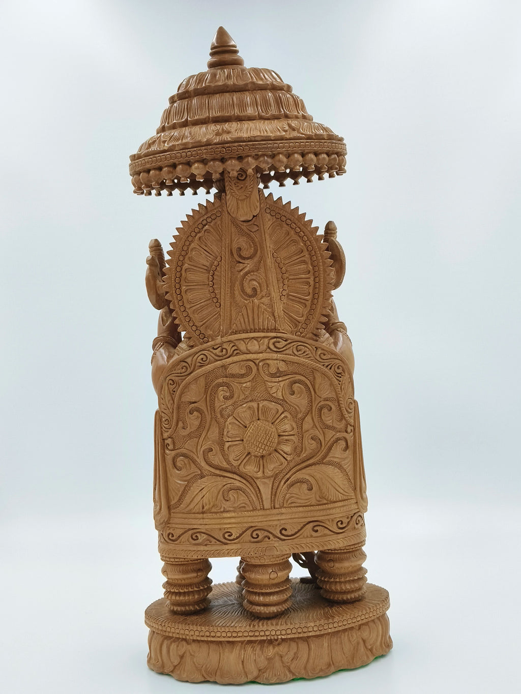 Back view of large sandalwood Ganesh sculpture with intricate carvings and decorative umbrella
