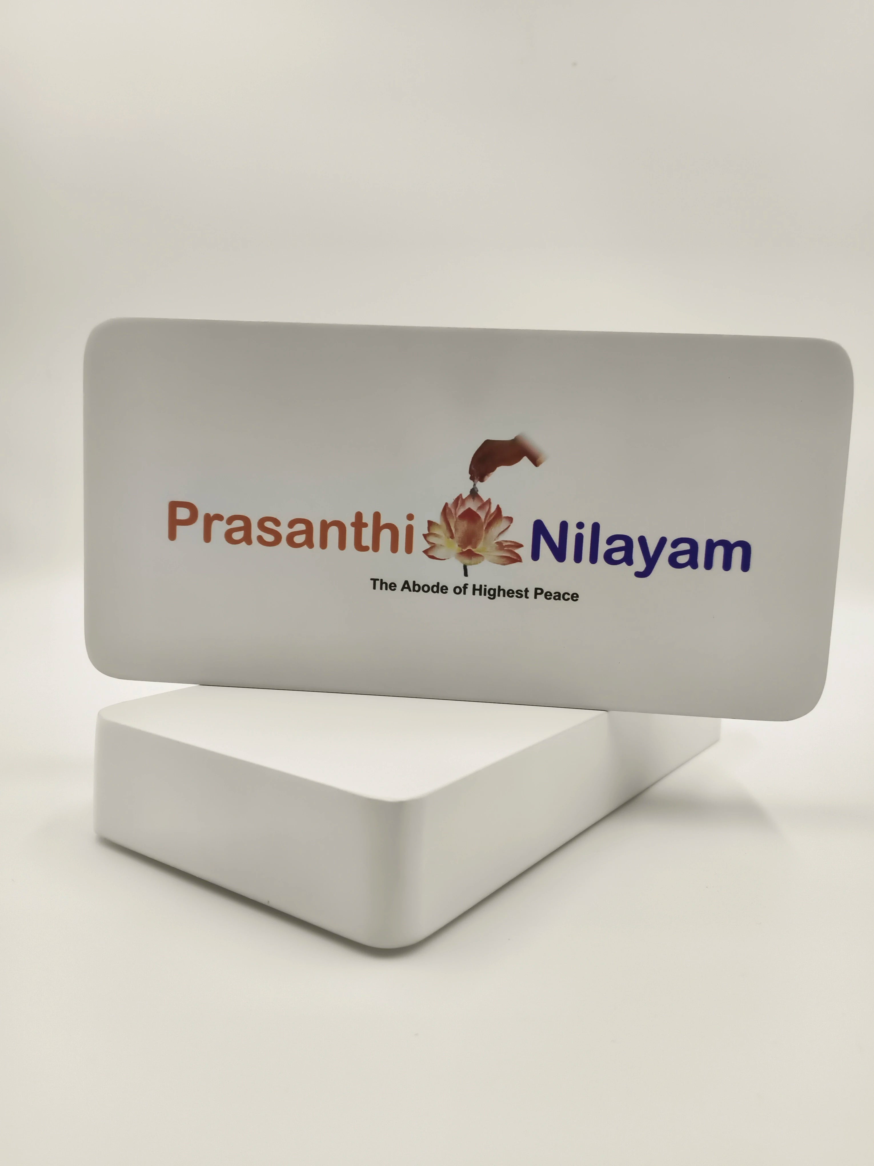 Wooden tabletop clock with Prashanthi Nilayam logo and text