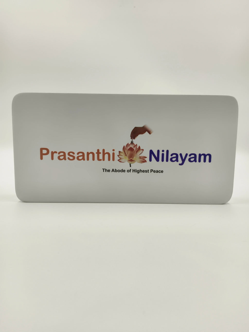 Small wooden tabletop clock featuring Prashanthi Nilayam logo and text