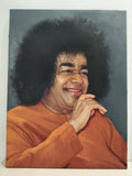 Large oil painting of Sai Baba in orange robe with smiling face and afro hairstyle on canvas