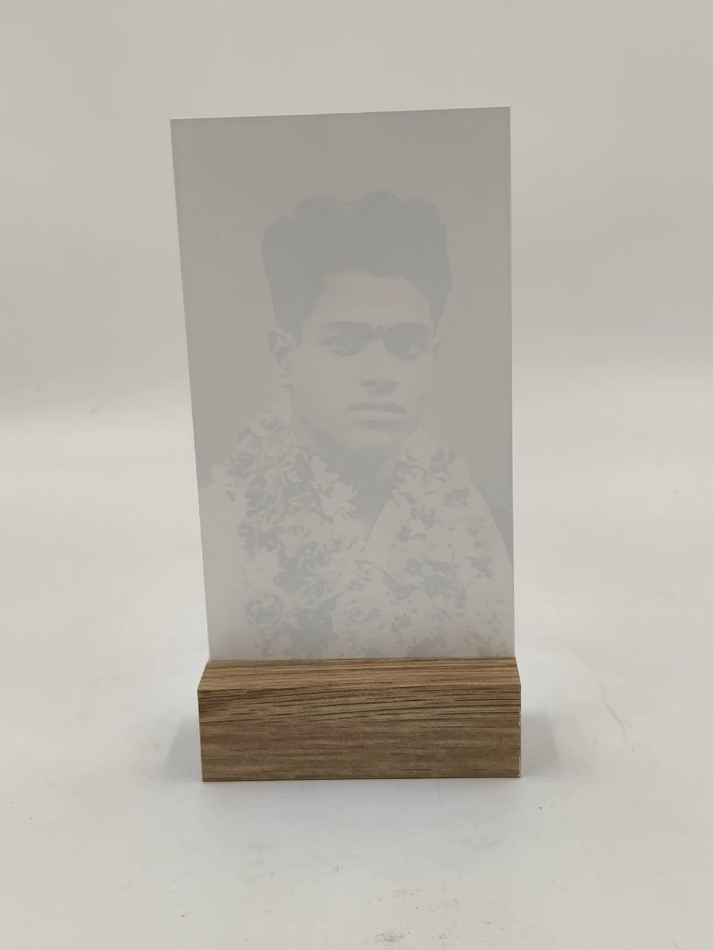 Glass photo display with wooden base holding a black and white portrait