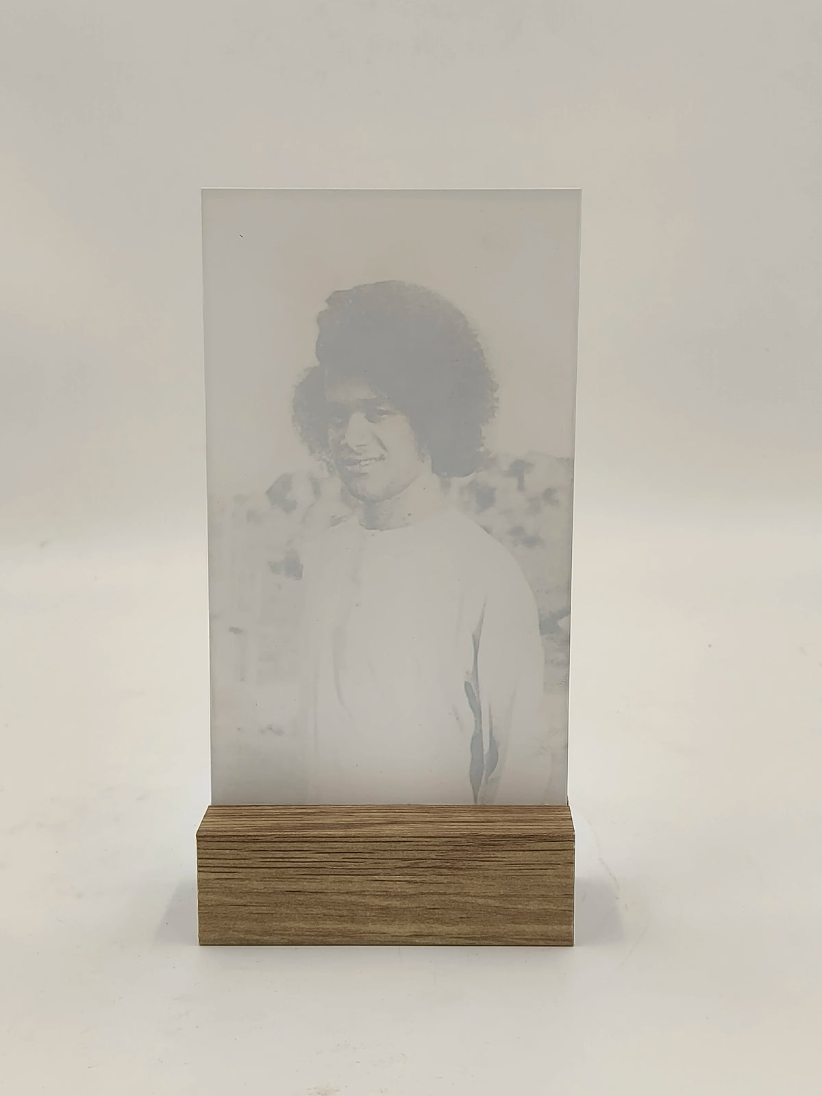 large glass display with wooden base featuring faded portrait