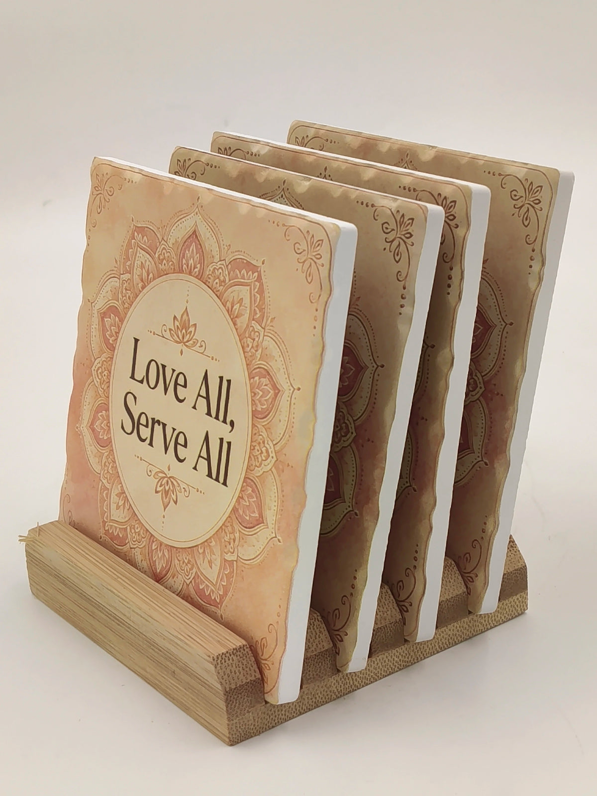 Set of ceramic coasters with 'Love All, Serve All' text and mandala design